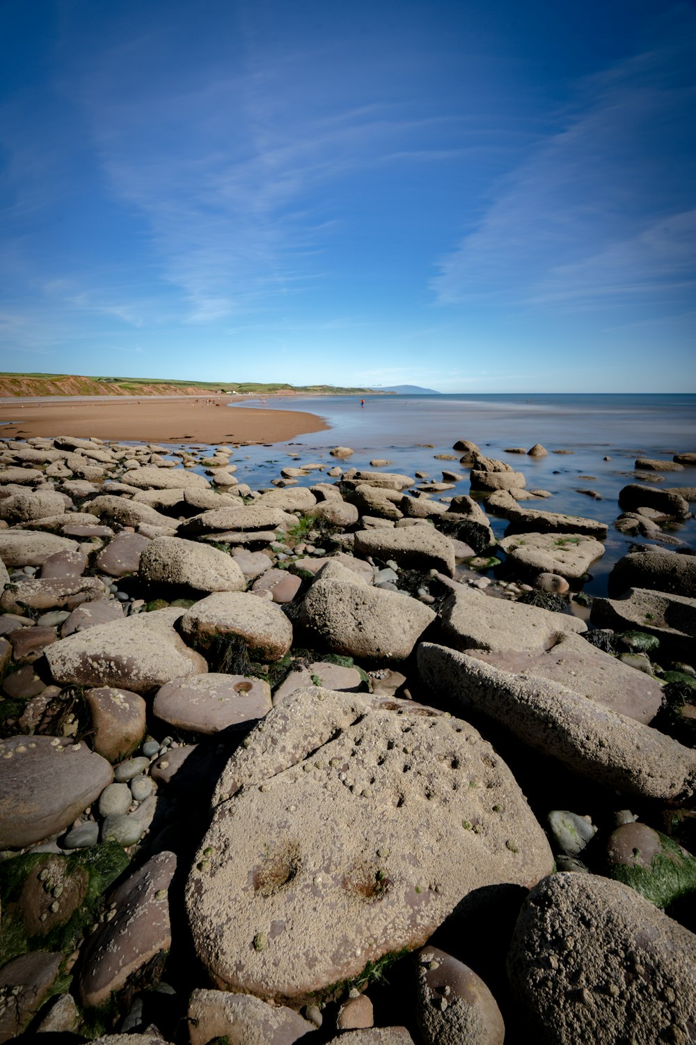a rocky beach with water and blue sky