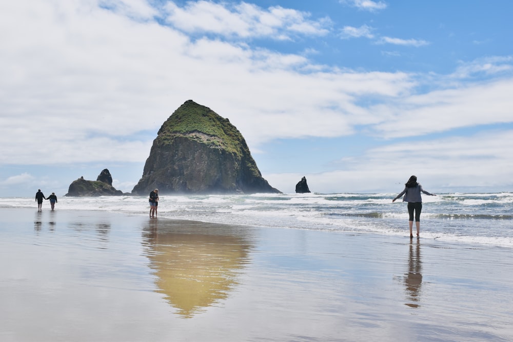 people walking on the beach with Haystack Rock in the background