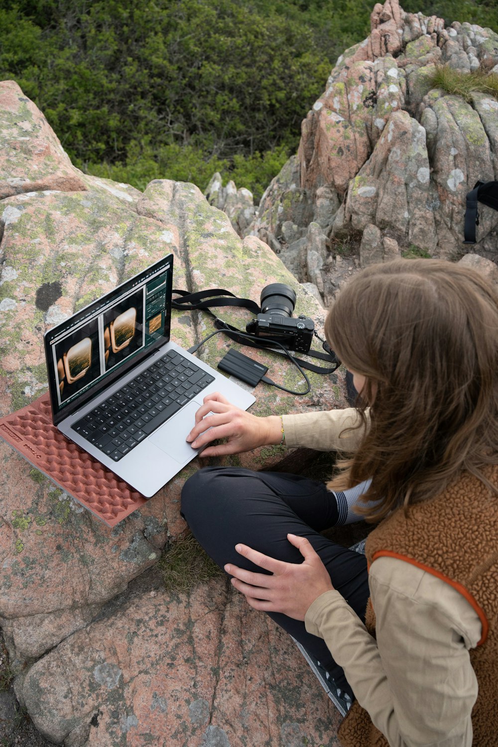 a person sitting on a rock using a laptop