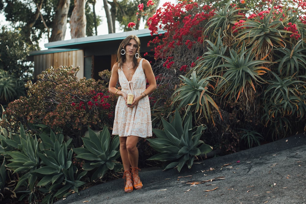 a woman wearing a white dress and talking on a cell phone