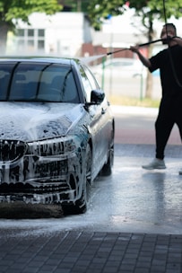 a person holding a gun next to a car that is on a brick road