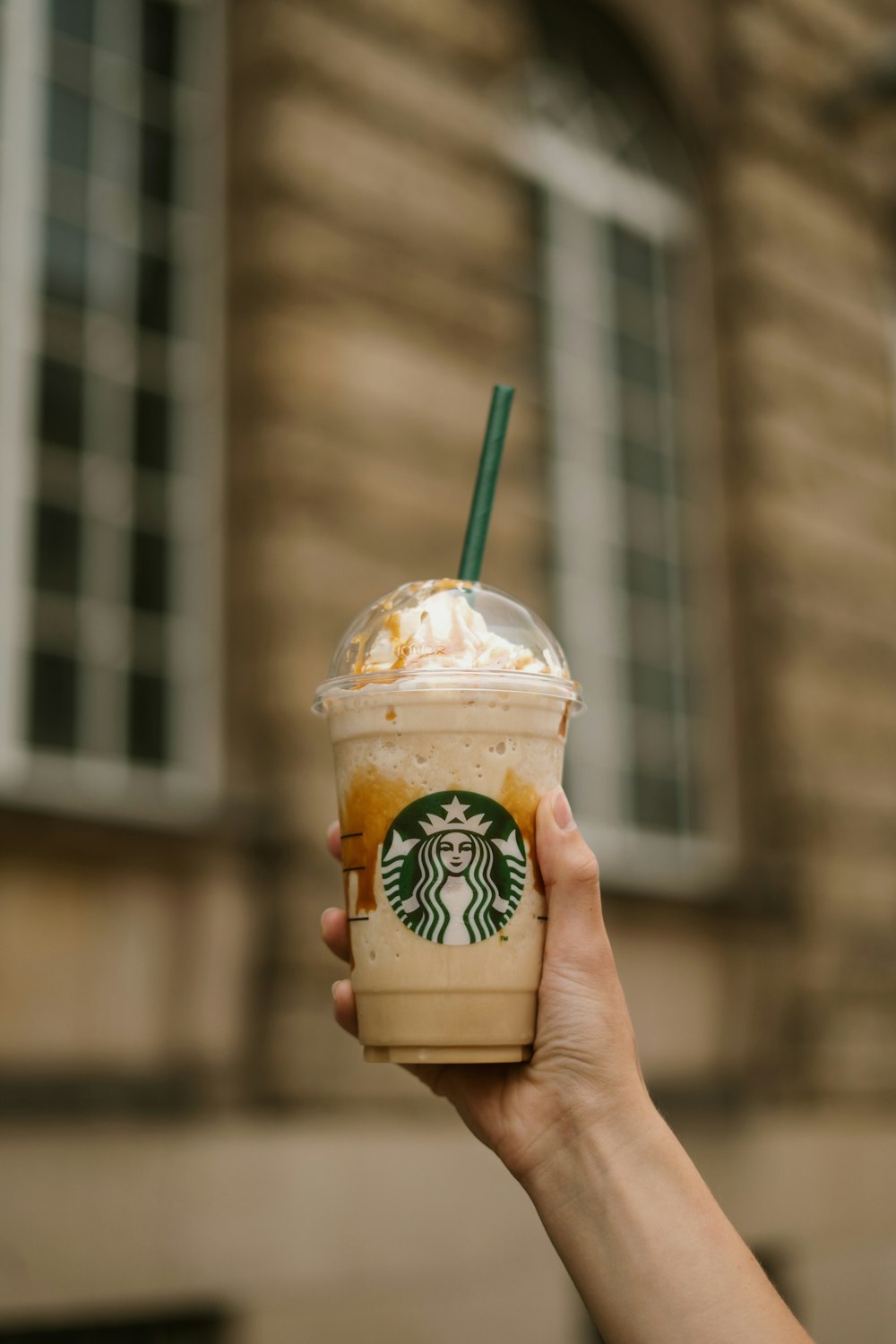 a hand holding a cup of ice cream with a straw