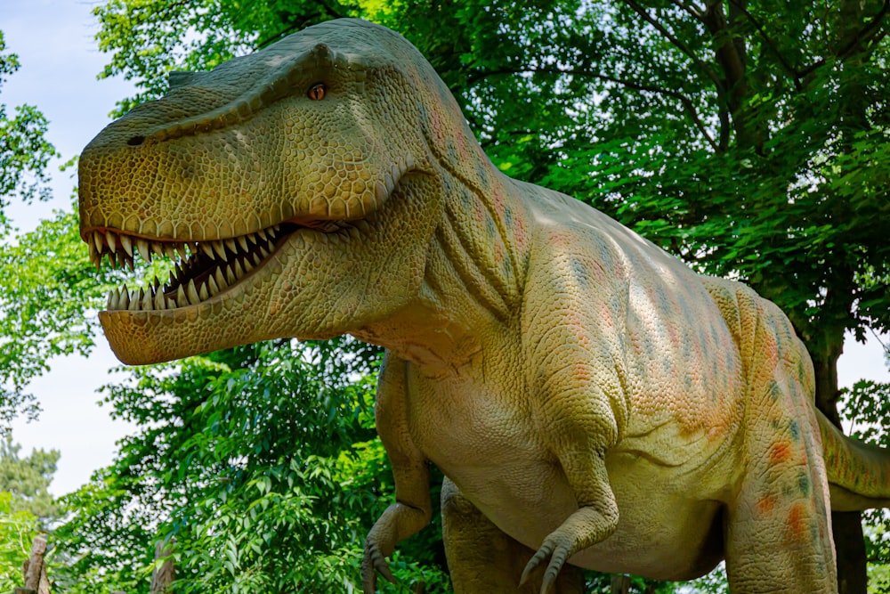 a dinosaur statue in front of trees