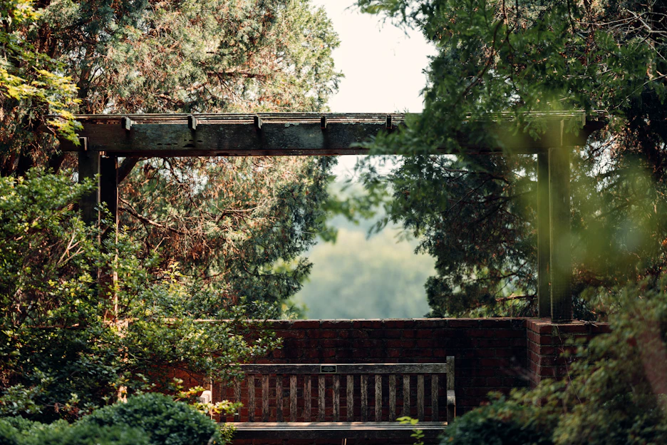 A serene backyard scene with a stylish pergola shade casting gentle shadows over a cozy seating area.