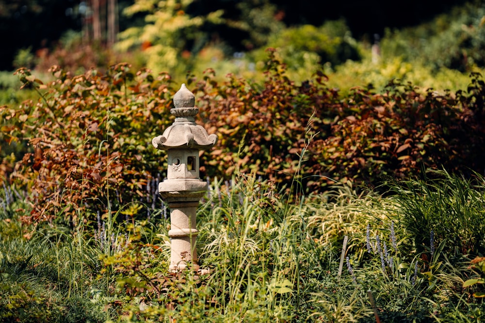 a small white and brown statue in a grassy area