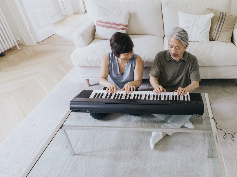 um homem e uma mulher que tocam um piano em um sofá