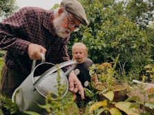 a man and a child looking at a plant