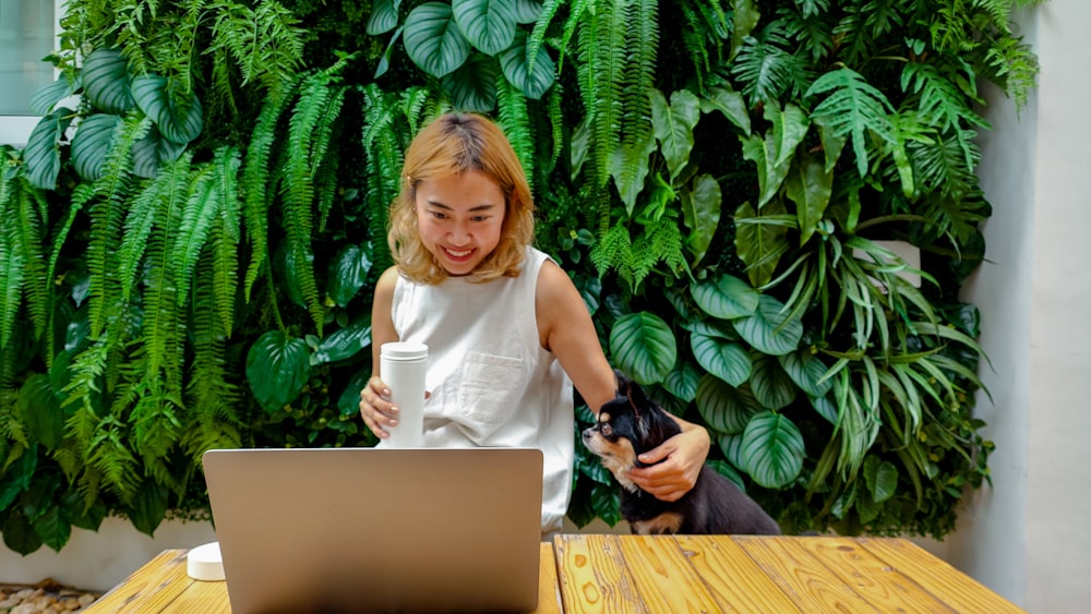 a woman sitting at a table with a laptop and a man holding a cup