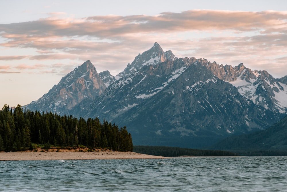 a body of water with trees and mountains in the background