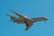 A private jet with extended landing gear flies against a clear blue sky, capturing the sleek design and modern engineering of the aircraft.