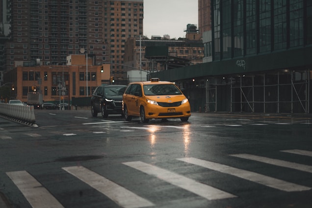 A taxi driving on a city street during the day.