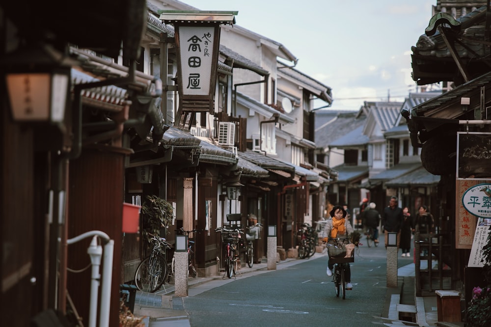 a person riding a bicycle down a narrow street