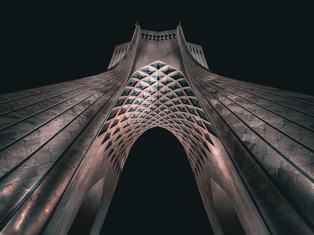 a tall building with a curved top with Azadi Tower in the background