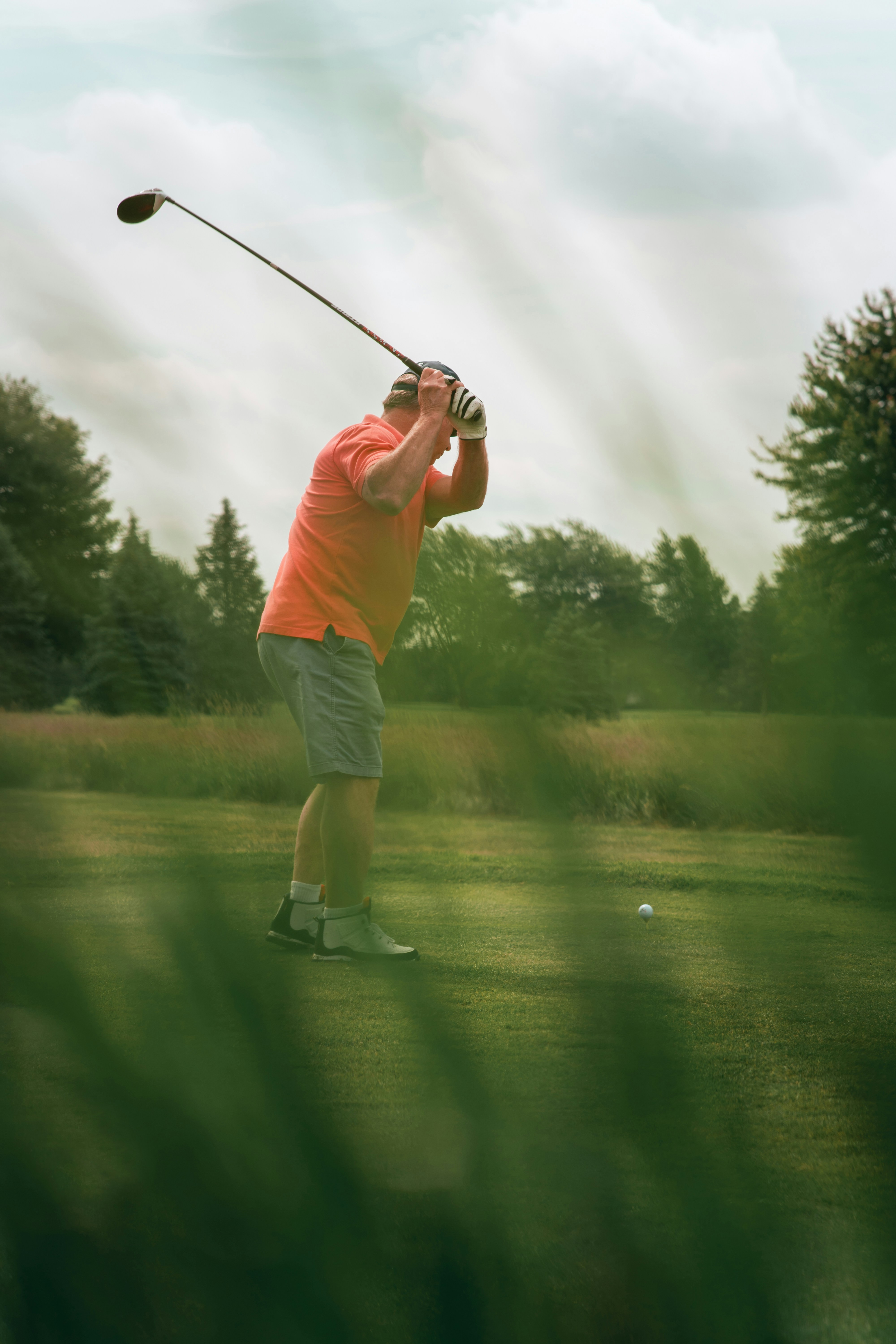 A golfer in mid-swing on a beautiful sunny day.