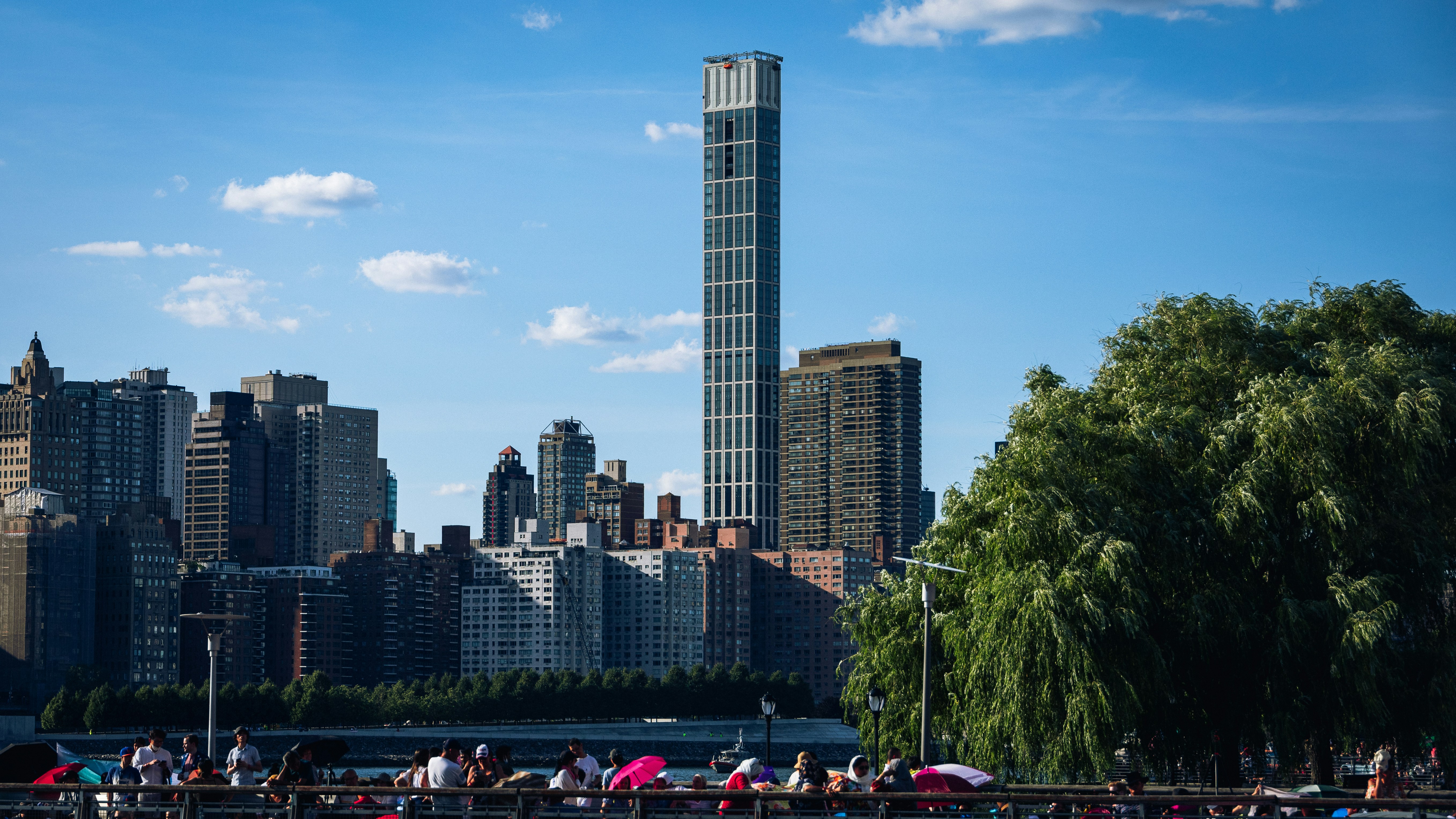a group of people sitting on a beach with a tall building in the background with Eureka Tower in the background