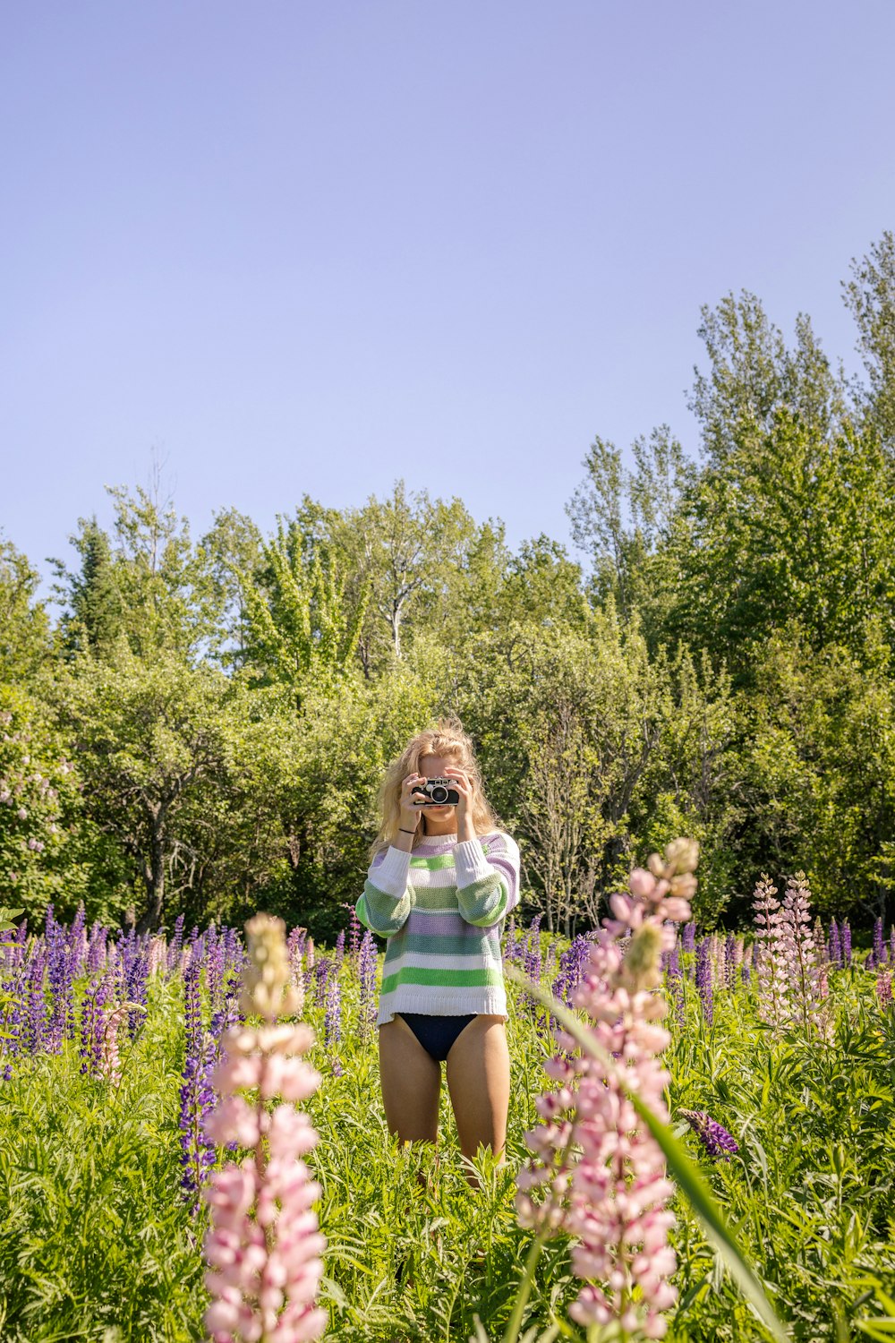 a woman taking a picture of a flower field