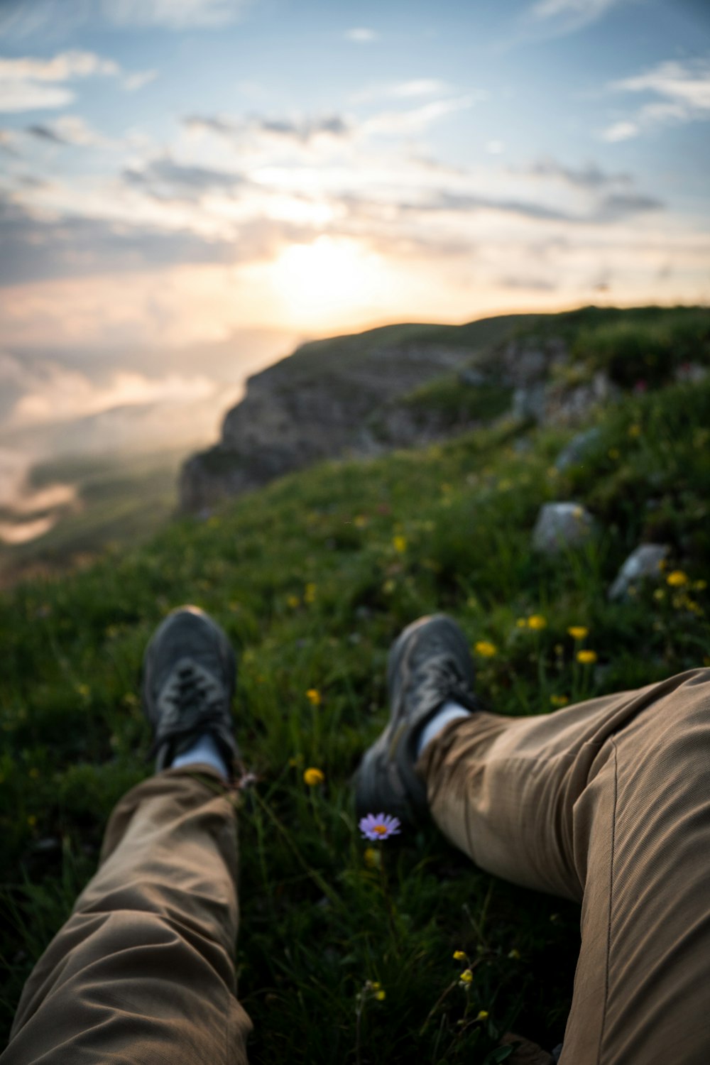 a person's feet in a grassy field with a mountain in the background