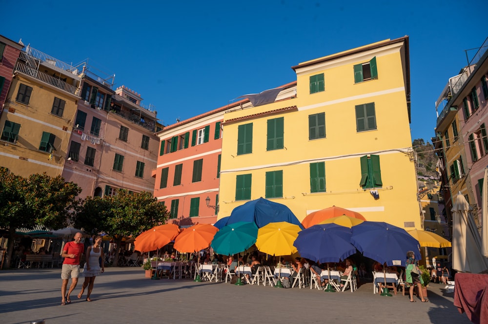 a group of people walking by a building with umbrellas