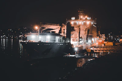 Nighttime shot of a ship illuminated by bright lights while docked for loading.
