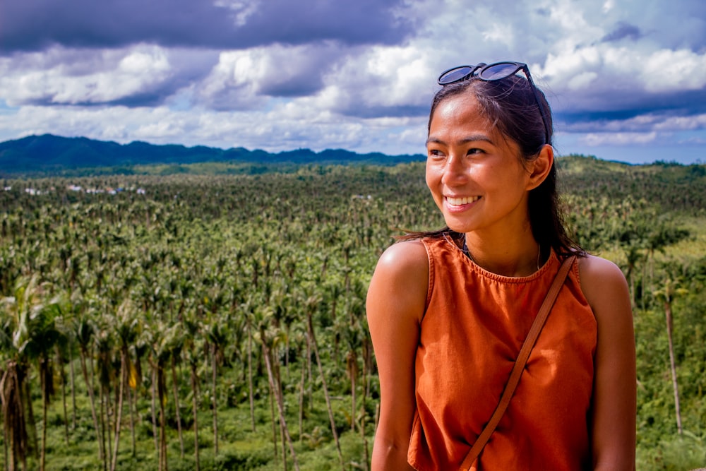 a woman standing in front of a lush green forest