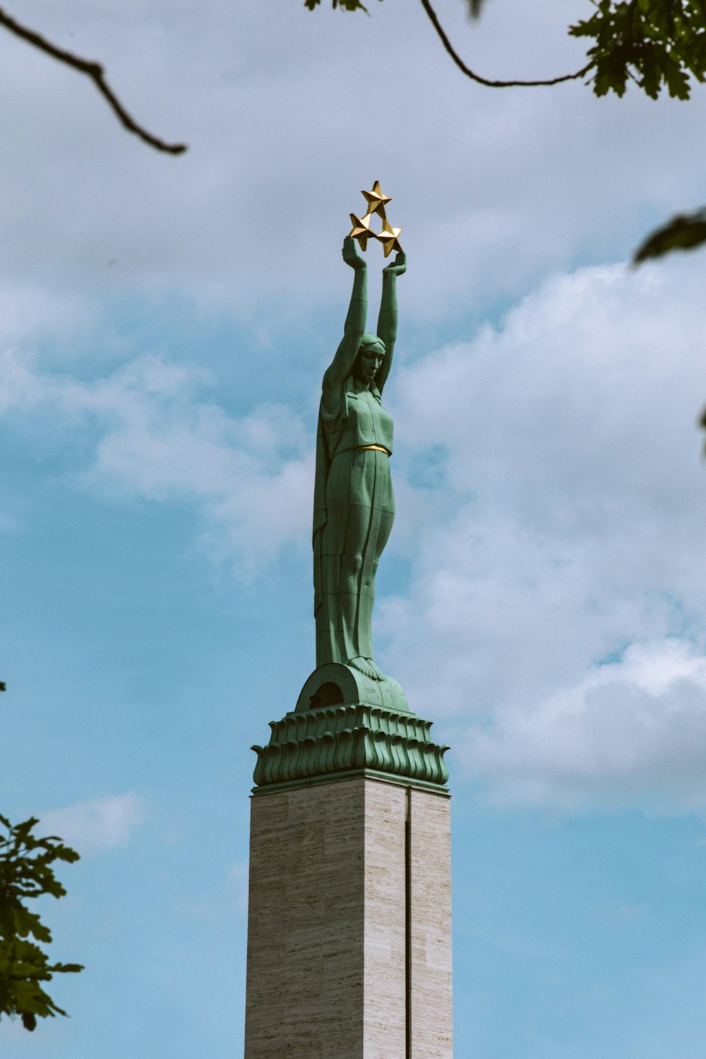 a statue of a person holding a torch with Freedom Monument in the background