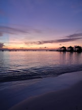 A serene overwater villa at sunset with turquoise waters reflecting the sky.