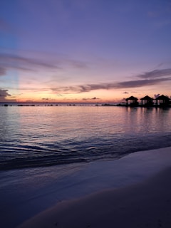 A serene overwater villa at sunset with turquoise waters reflecting the sky.
