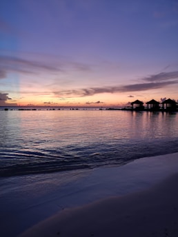 A serene overwater villa at sunset with turquoise waters reflecting the sky.