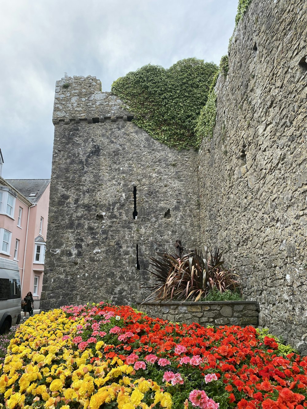 a stone building with a garden of flowers in front of it