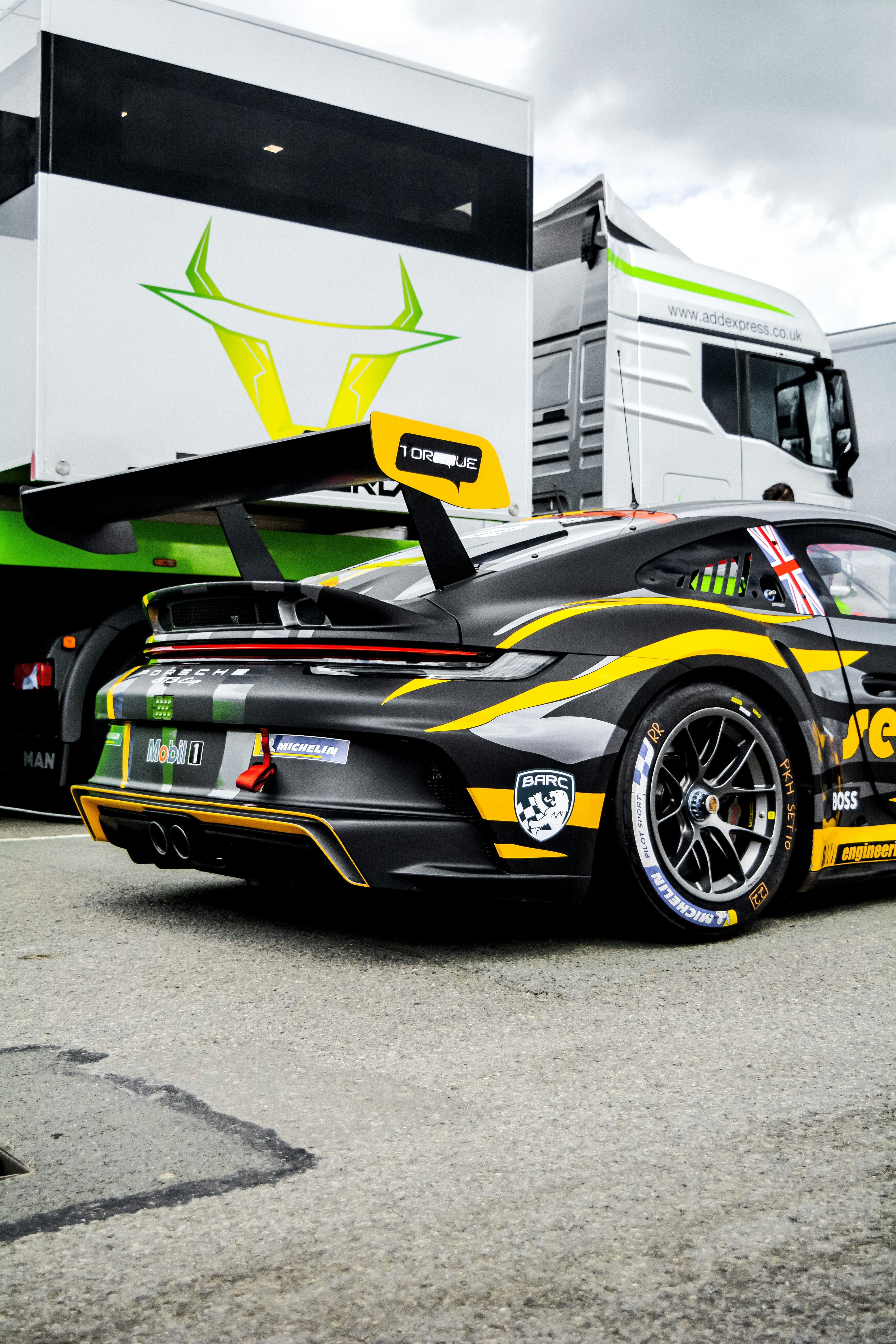 a race car parked in front of a large white truck