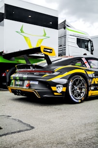 a race car parked in front of a large white truck