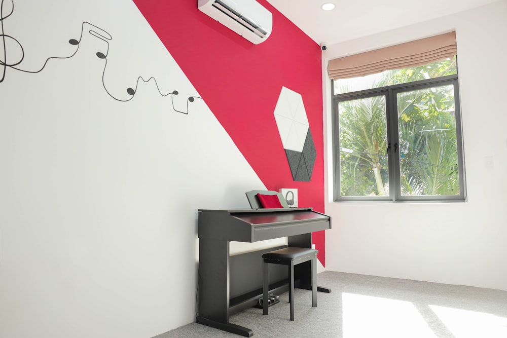 a room with a desk and a window with a red and white wall