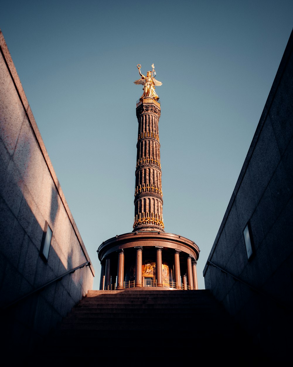 a tall tower with a gold statue on top