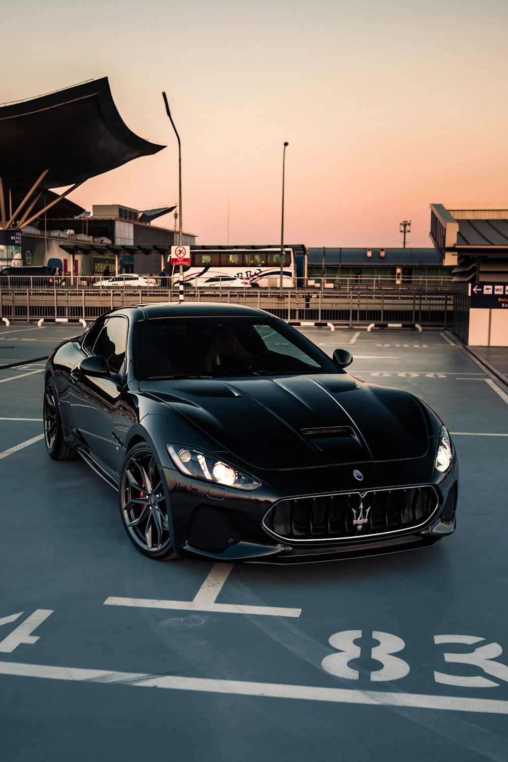 a black sports car parked on a road with a building in the background