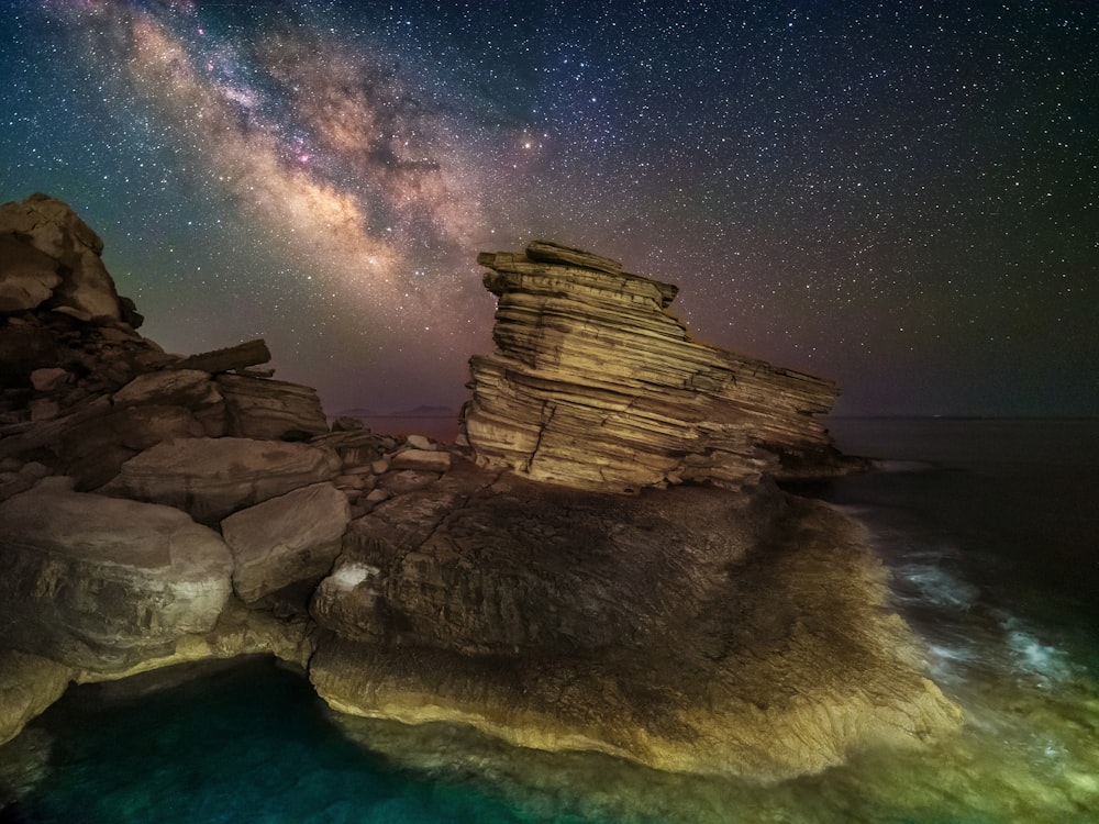 a rocky cliff with a star filled sky above it