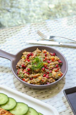 Close-up of a nutritious meal featuring pomegranates and leafy greens on a terracotta plate.