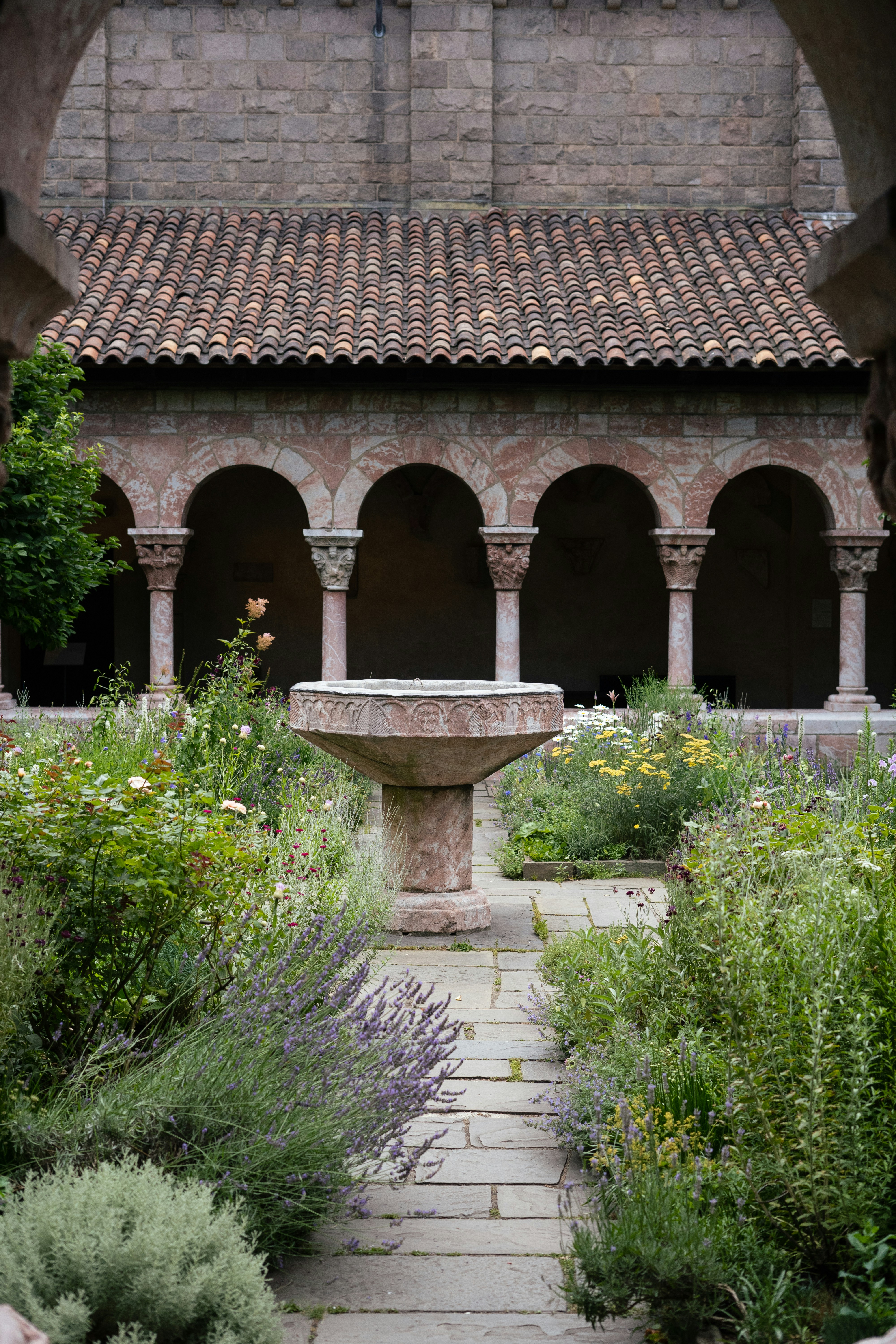 a stone building with a fountain with The Cloisters in the background
