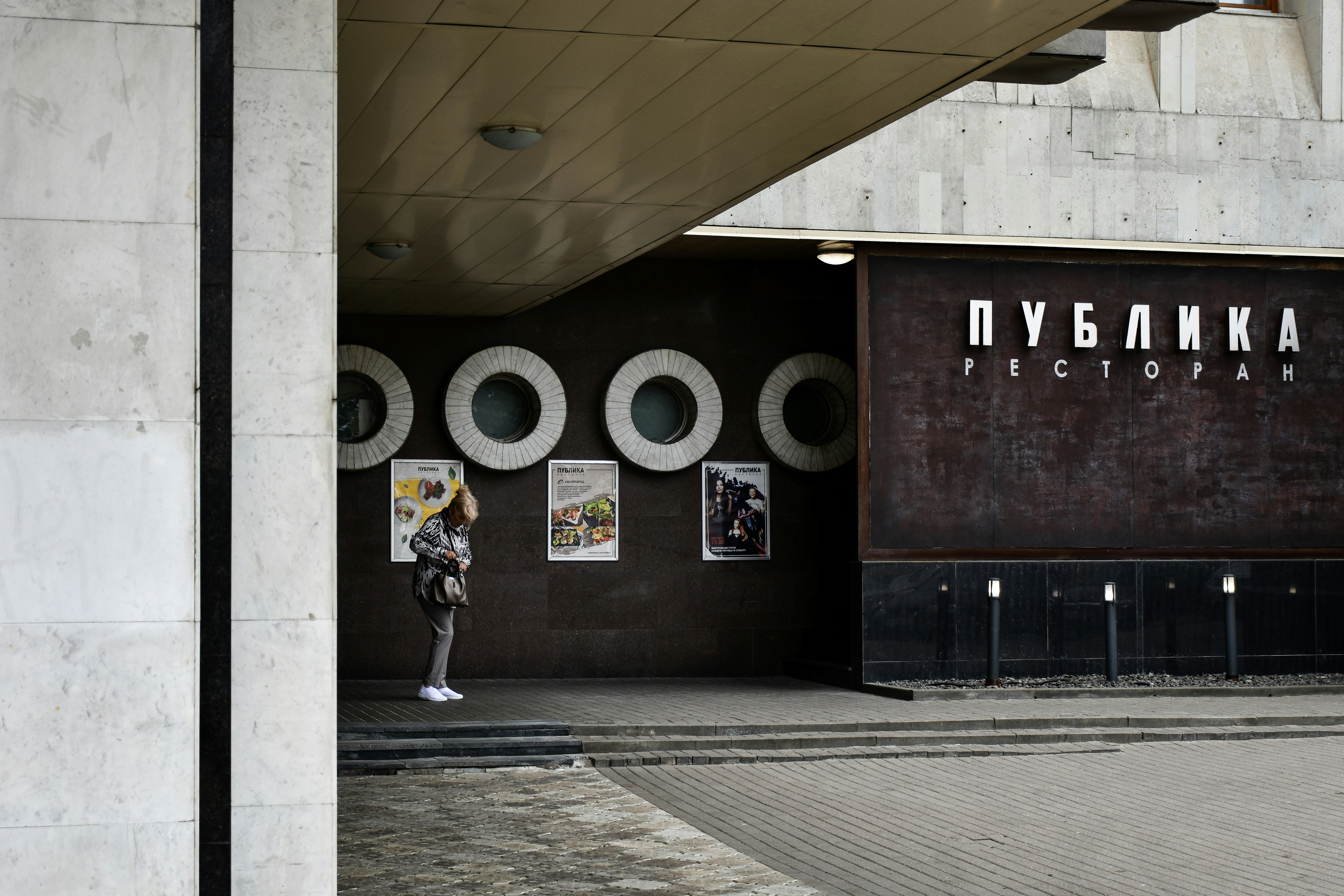 a person standing in front of a building with a sign on it