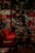 A dimly lit, elegant restaurant interior with red chairs lined up at wooden tables. Wine glasses are neatly arranged, and decorative light fixtures hang from the ceiling. The reflection patterns on glossy surfaces create an upscale ambiance.