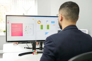 A professional analyzing digital marketing data on multiple screens in a modern office.