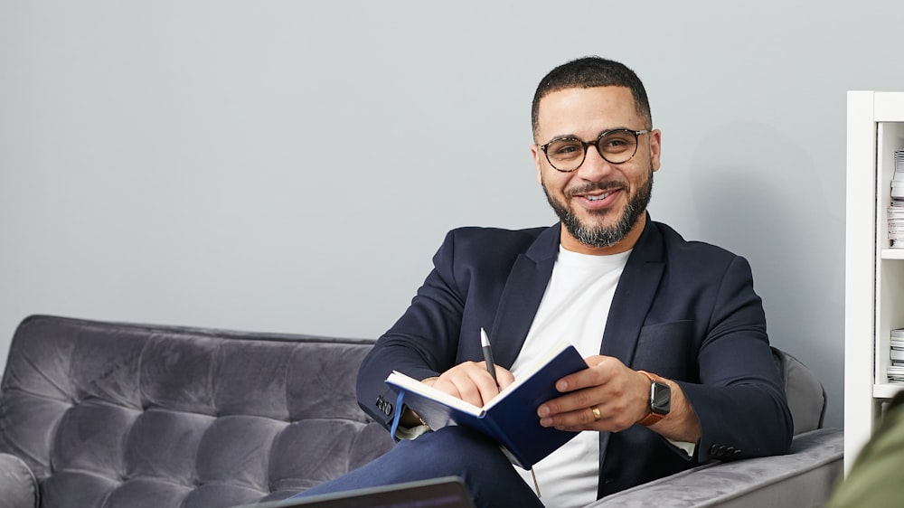 a man sitting on a couch and holding a pen