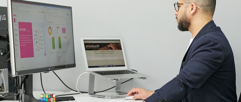 a man sitting at a desk with a laptop and a computer