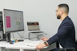 a man sitting at a desk with a laptop and a computer