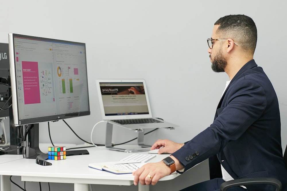 a man sitting at a desk with a laptop and a computer