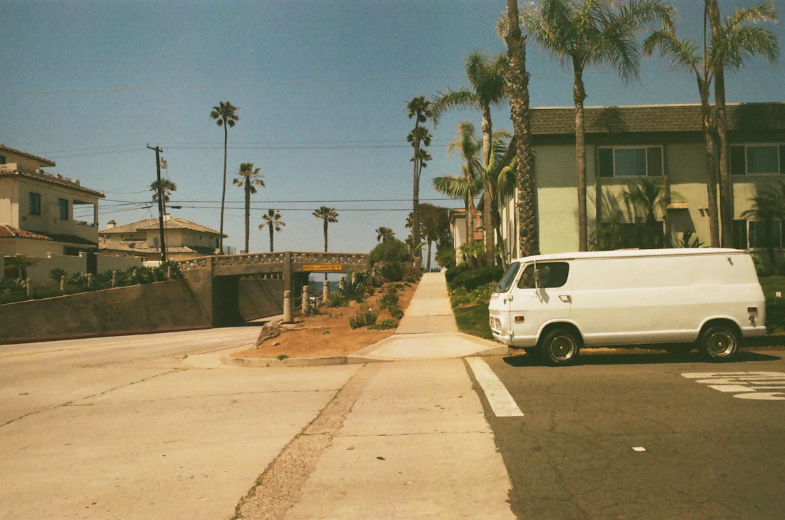 A plain white van with no signwriting parked on a quiet residential street