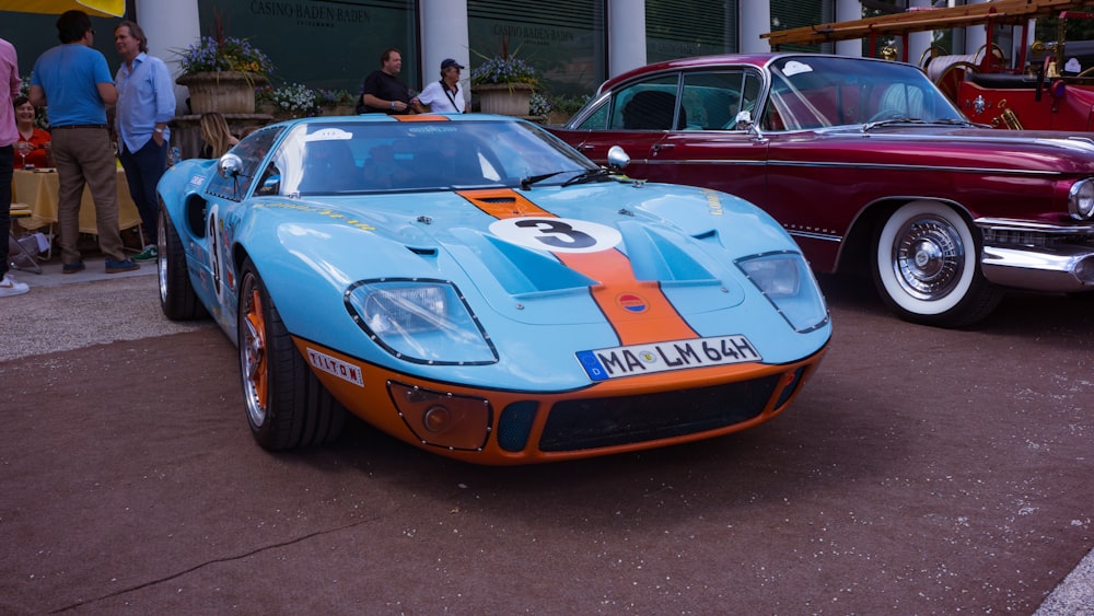 a blue and red sports car parked next to other cars