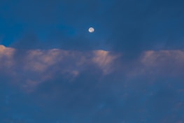 A peaceful night sky with a glowing full moon surrounded by gentle clouds.