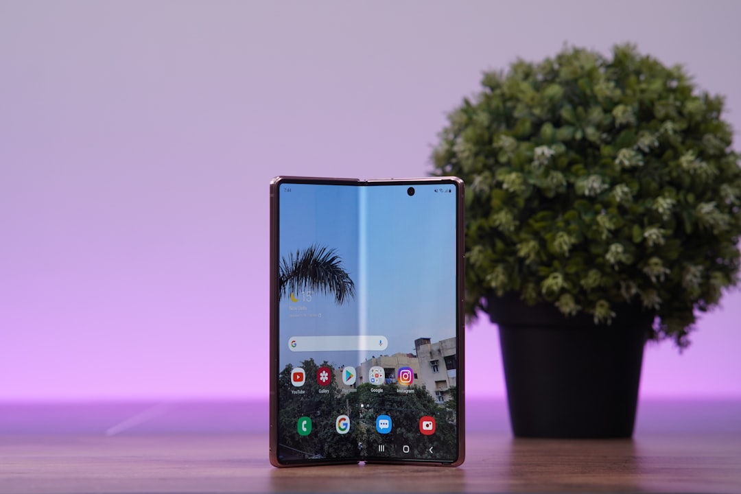 a cell phone with a tree in the background, A foldable phone standing on a table.</p></figure><p>Samsung Galaxy Z Fold 2 standing on a table.