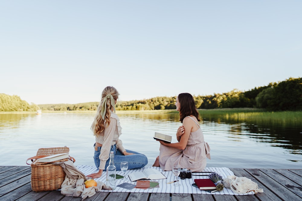 two women sitting on a dock