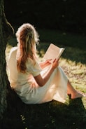 a person sitting on the ground reading a book